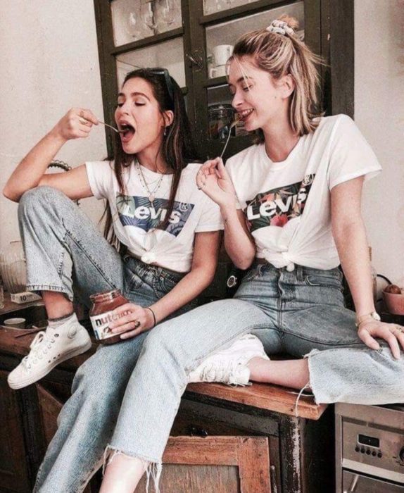 Chicas comiendo Nutella sentadas en escritorio