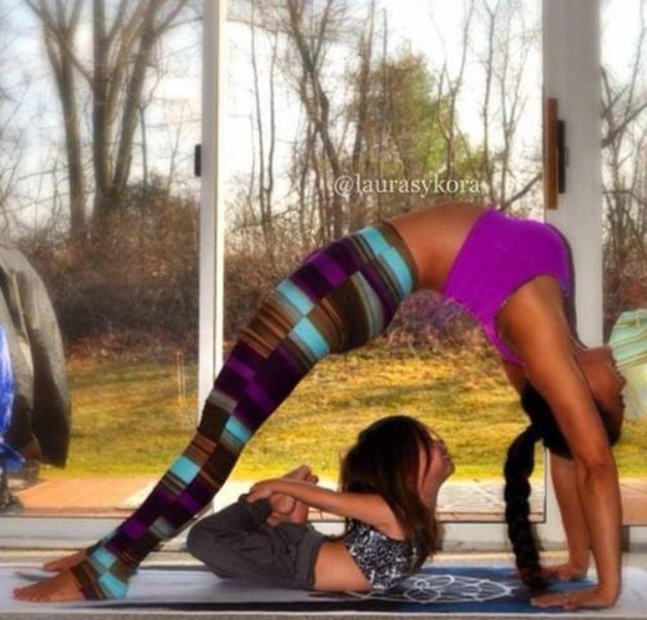 Pose de yoga donde una niña esta debajo de su madre 