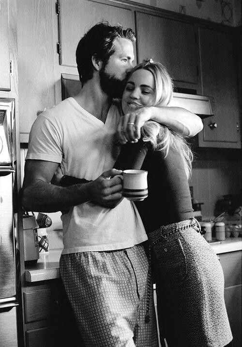 pareja de novios abrazados en la cocina tomando café 