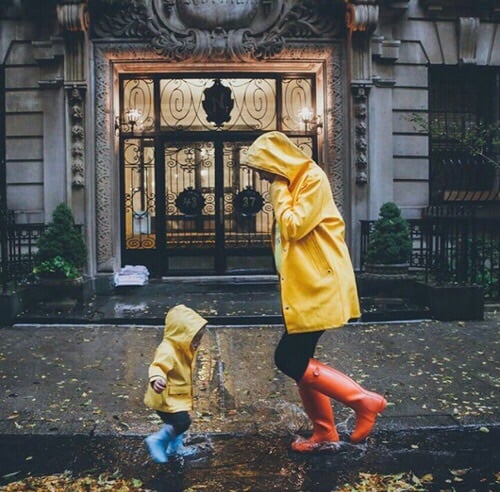 Madre e hija juegan en la lluvia con impermeables amarillos