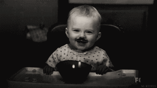 bebe con bigote sentado comiendo de un tazón