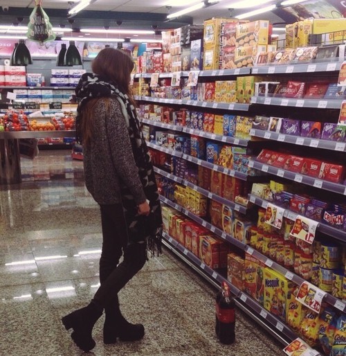 mujer frente a un estante de comida en el supermercado 