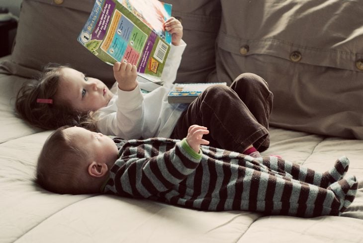 Hermana pequeña leyendo a su hermanita bebé