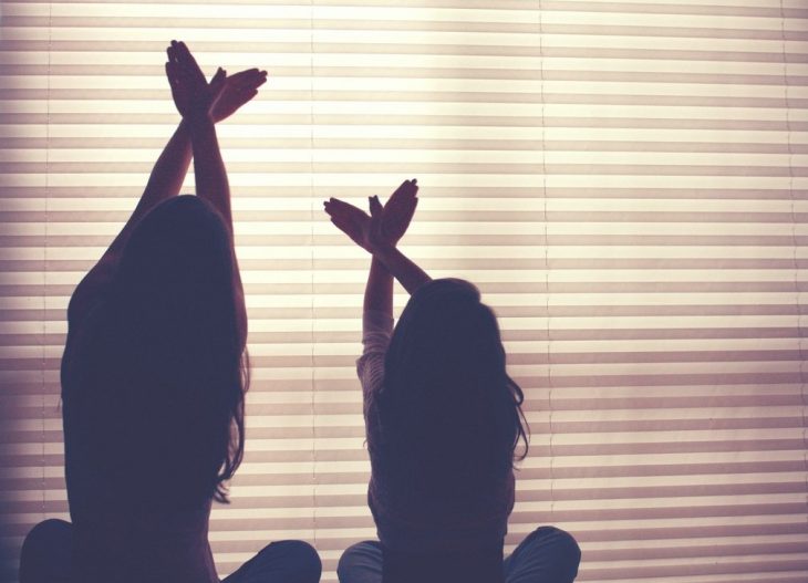 Hermanas haciendo poses en una ventana 