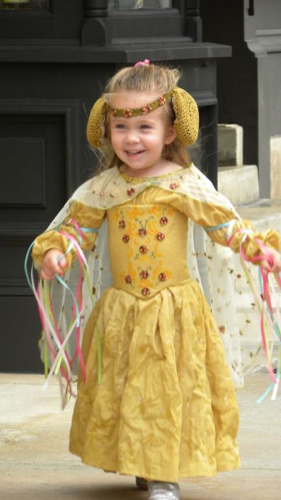 niña corriendo con un vestido amarillo y orejeras amarillas 