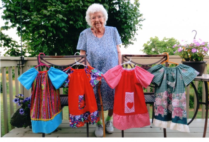 Una donna di 99 anni con alcuni degli abiti che produce ogni giorno 