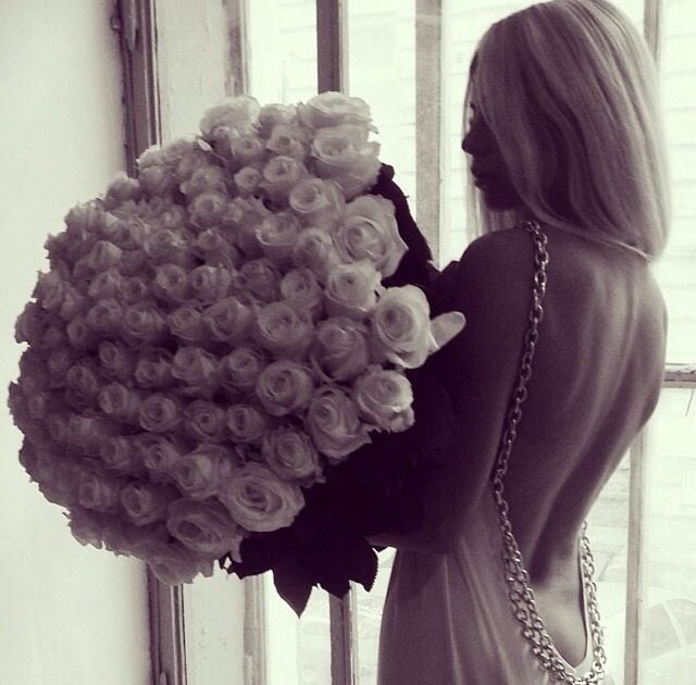 chica cargando ramo de rosas blancas con vestido color blanco con espalda descubierta