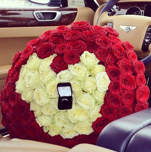 ramo de flores en forma de corazón rojas y blancas con un anillo dentro de ellas 