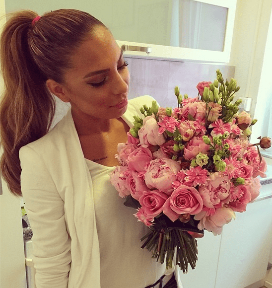 mujer vestida de blanco viendo un ramo de rosas rosas 