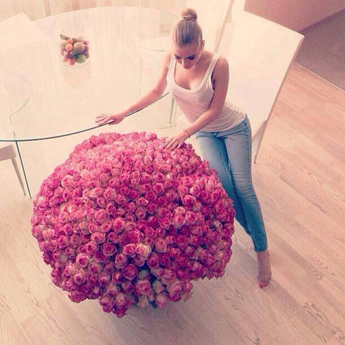 mujer sentada en una mesa vestida de azul y blanco observando un ramo de flores 