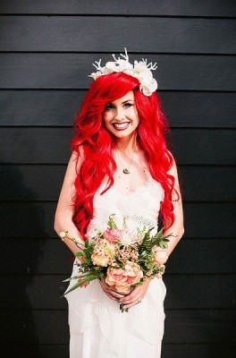 chica de cabello rojo vestida de novia sujetando un ramo de rosas 