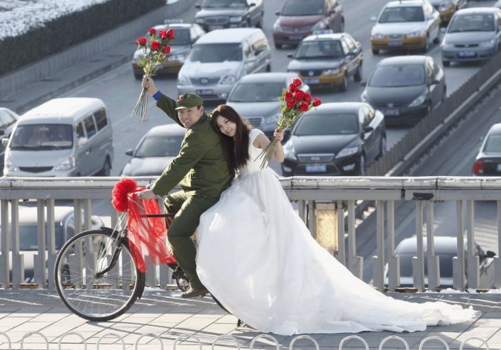 novios sobre una bicicleta parados en medio de un puente