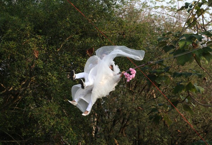 novios colgando de una tirolesa en medio del bosque