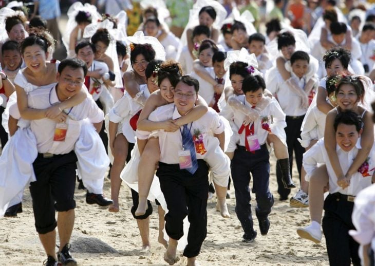 parejas de novios corriendo pro una playa en china 