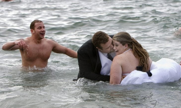 novios besandose en medio del mar 