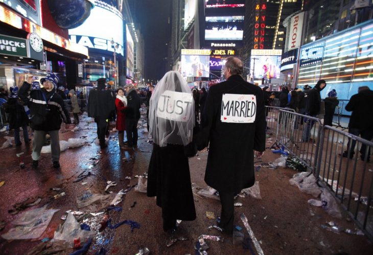personas caminando por una calle de new york con un letrero en la espalda de recién casados 