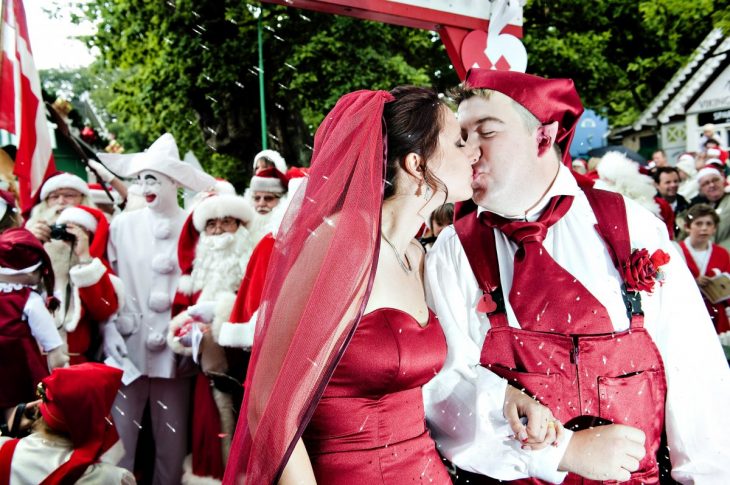 novios vestidos de rojo celebrando su boda junto a personas vestidas de santa claus 