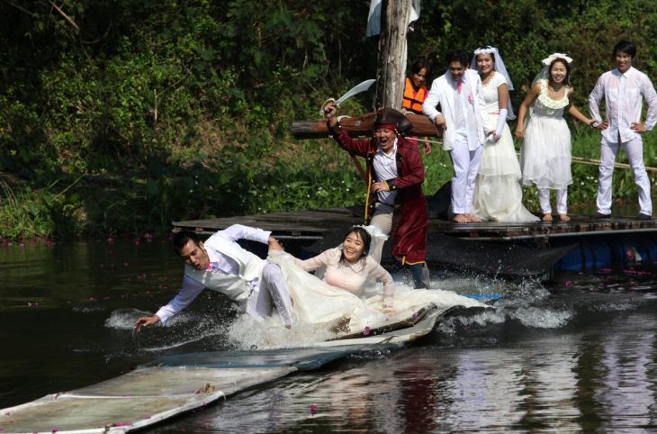 novios corriendo a través del agua siendo perseguidos por un señor vestido de pirata 