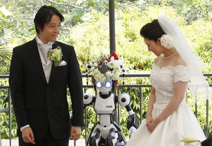 novios en una ceremonia de boda siendo casados por un robot 