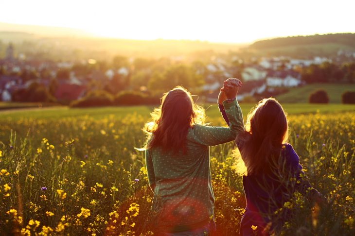 hermanas agarradas de la mano en el campo viendo el atardecer 