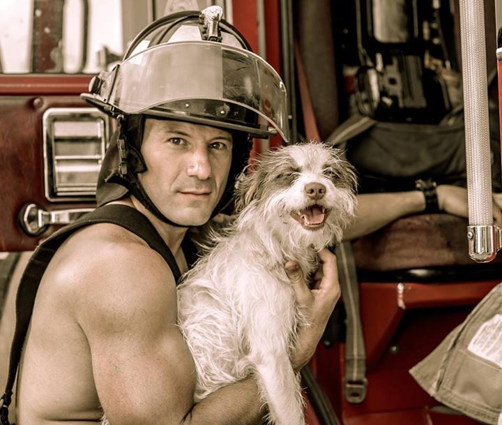 Bombero junto a un camión cargando un perro 