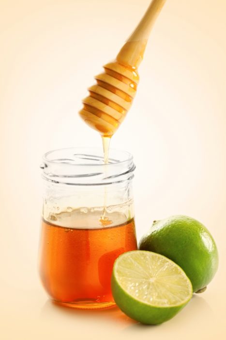 Frasco de miel y limones a un costado 