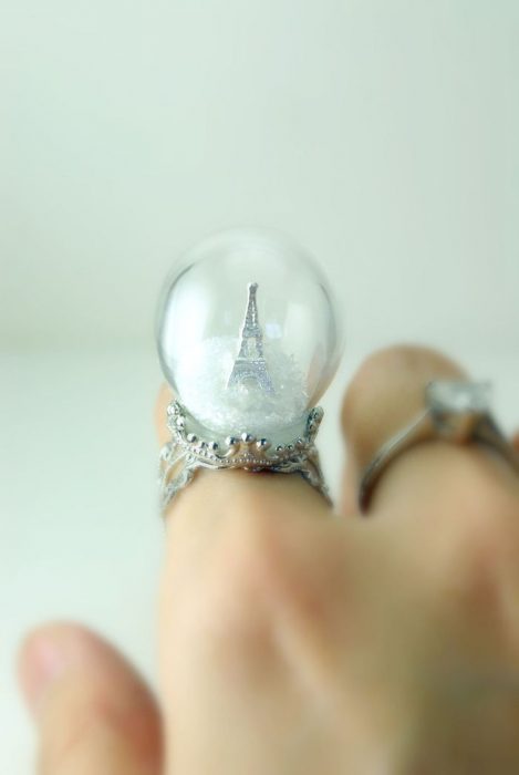 fotografía de anillo con una bola de nieve y una pequeña figura de la torre eiffiel en su interior