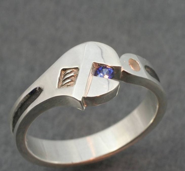 Fotografía de anillo en forma de llave inglesa sosteniendo un zafiro de color azul 