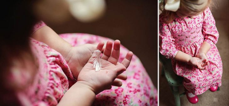 niña sentada en una silla usando vestido y zapatos de color rosa sosteniendo una pluma en sus manos 