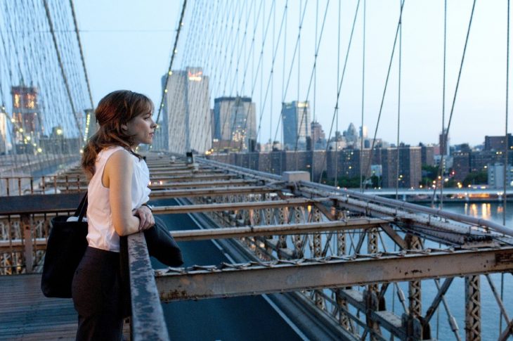 mujer parada en un puente admirando la ciudad 