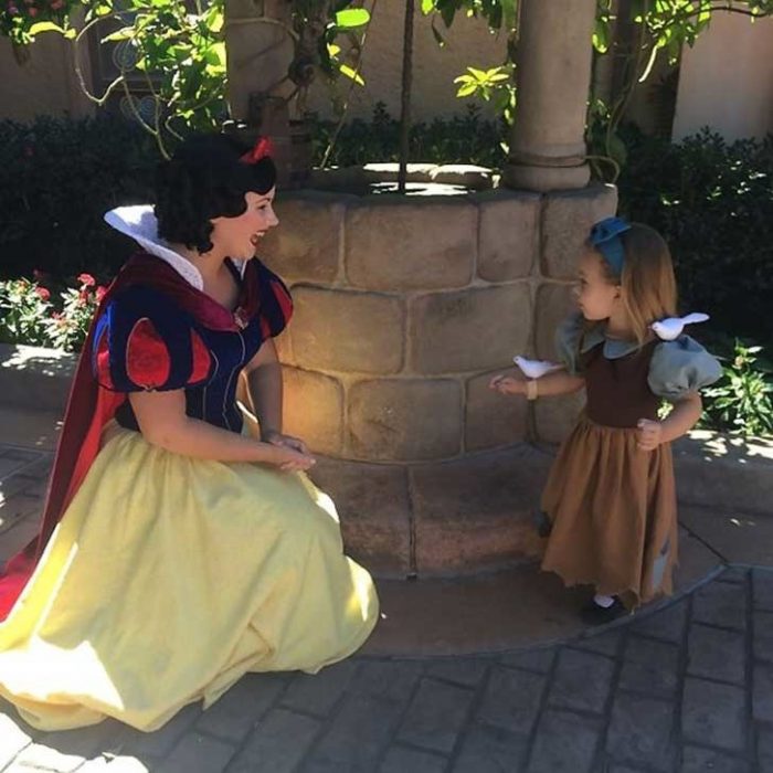 niña con un pájaro en su mano acompañada de una mujer vestida de blanca nieves 