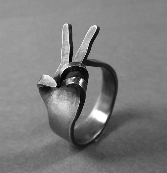 imagen de anillo en color gris haciendo con el símbolo de amor y paz conformado por unos dedos 