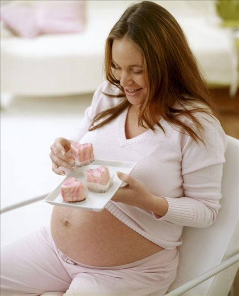 mujer embarazada comiendo pasteles 