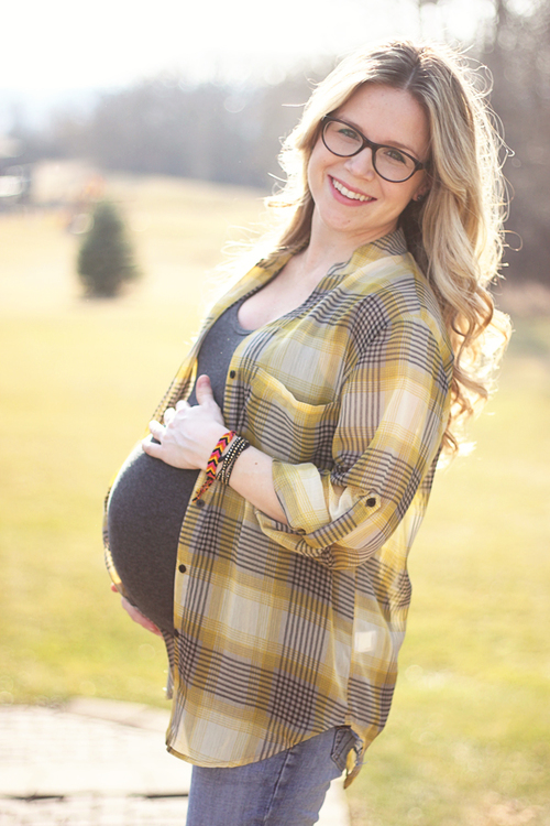 mujer embarazada con gafas parada en medio de un jardín