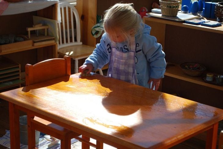 Niña pequeña limpiando una mesa