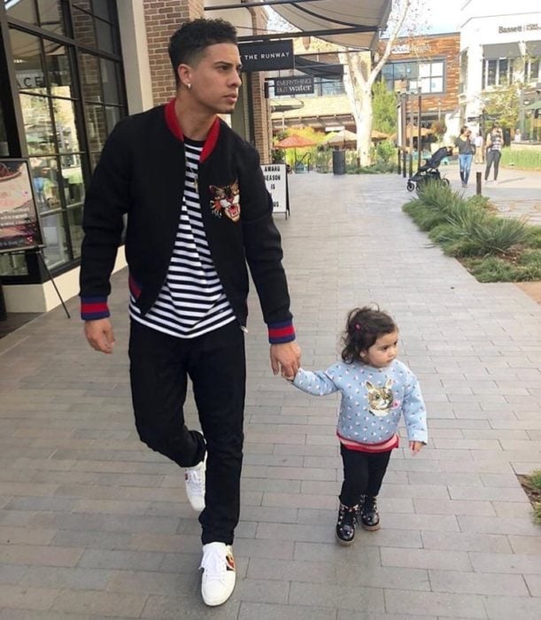 Papá joven paseando con su hijita de la mano