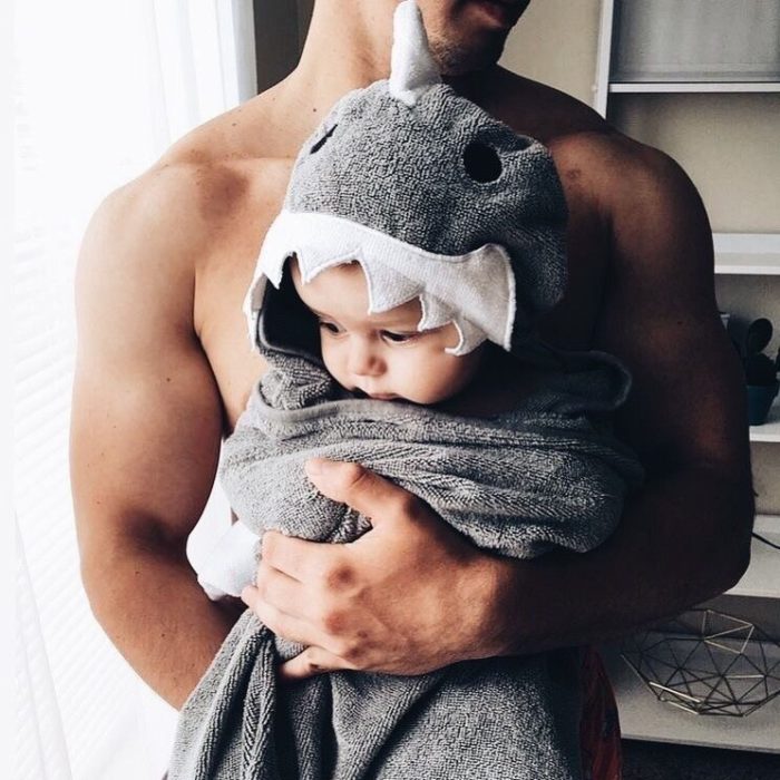 Papá con bebé en brazos envuelta en una toalla de tiburón