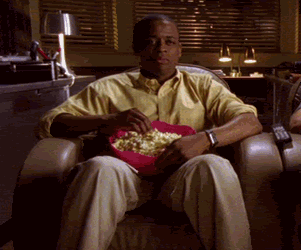hombre sentado en un sofá comiendo palomitas frente al televisor