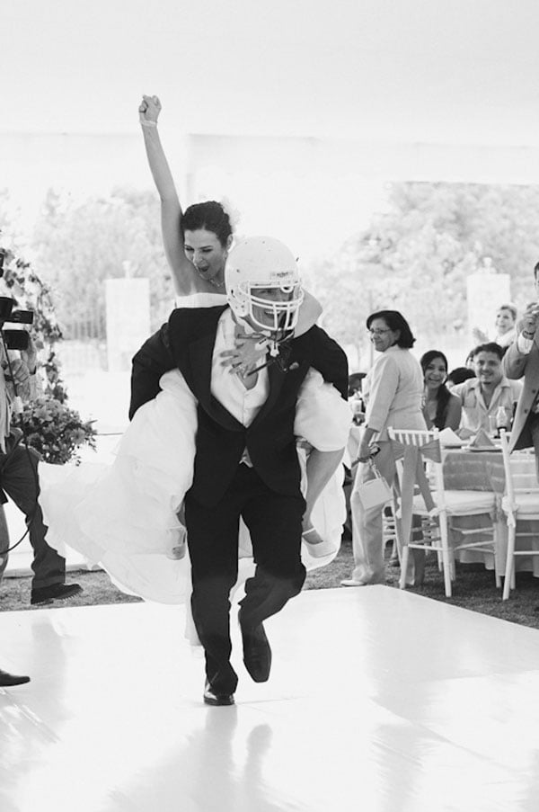 novio usando un casco de futbol americano mientras carga su una novia en la espalda 