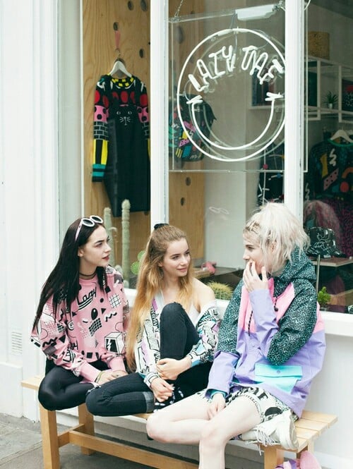 amigas sentadas hablando afuera de una tienda 