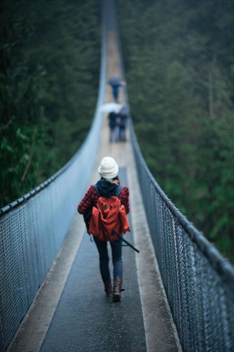 chica con equipaje caminando sobre un puente 