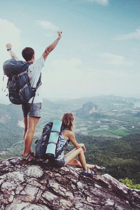 Pareja cargando equipaje al filo de una montaña