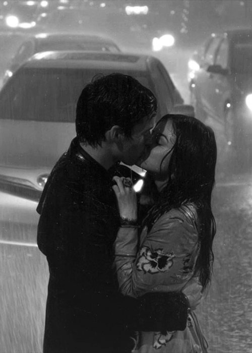 pareja dándose un beso bajo la lluvia 