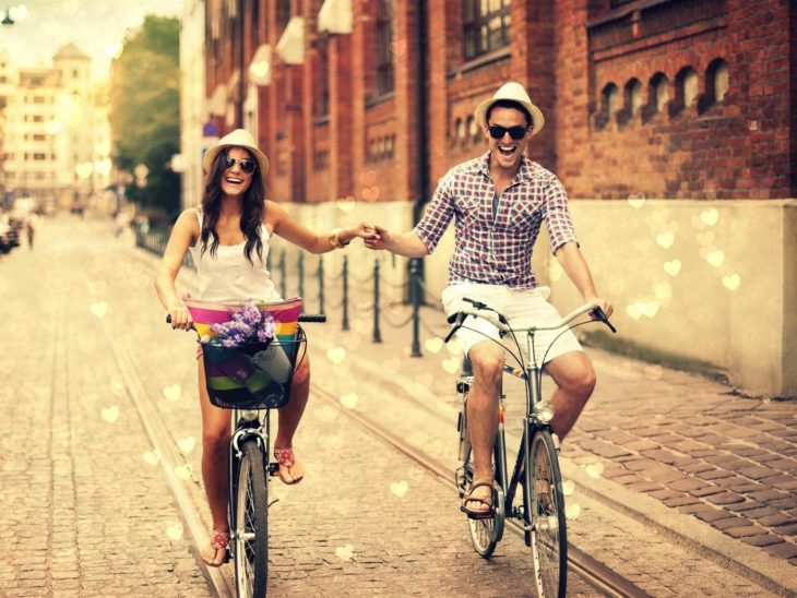 Chicos enamorados en bicicleta por una calle 