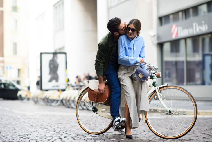 Pareja de novios en una bicicleta dándose un beso 