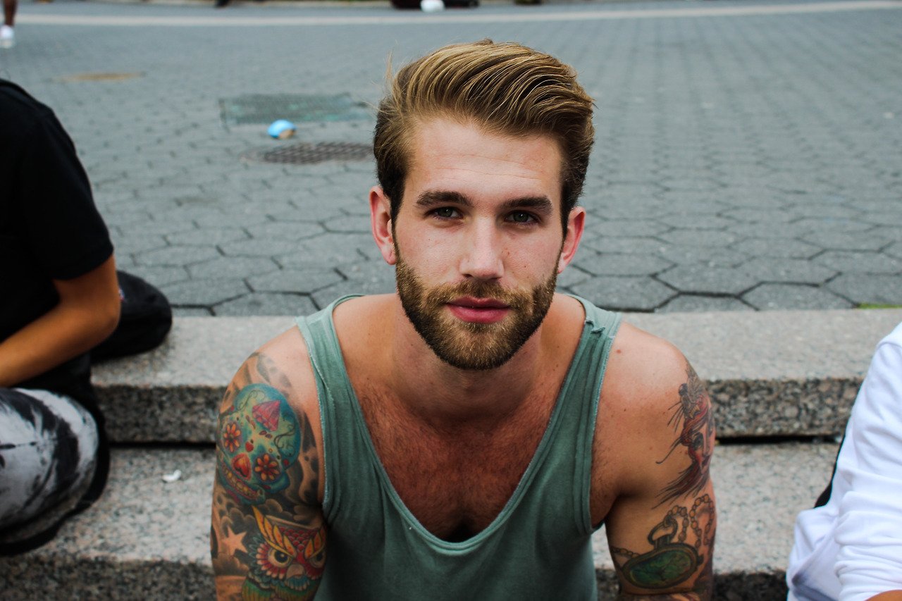 Hombre con barba y tatuajes en el cuerpo.