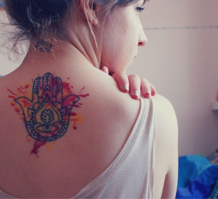 Chica con un tatuaje de la mano de fatima en la espalda