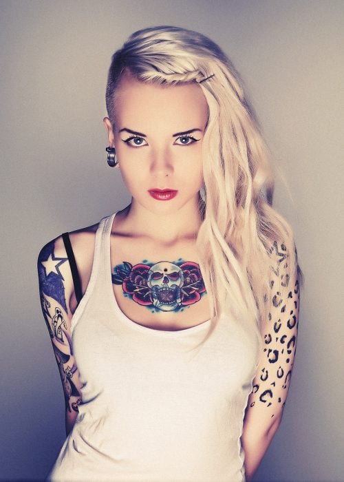 Chica con mirada seductora y tatuajes en brazo y pecho 