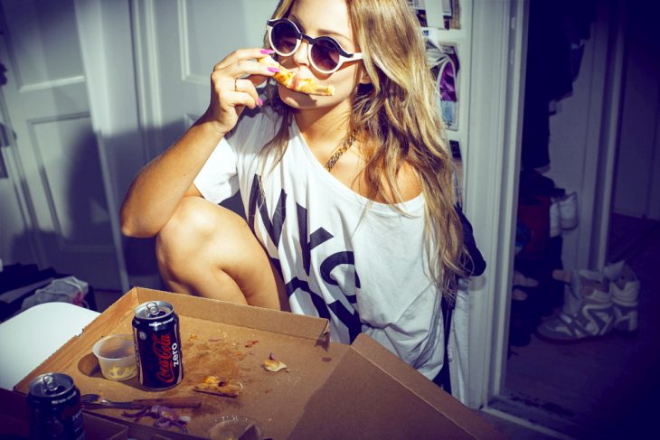 Chica comiendo pizza con una coca cola zero 