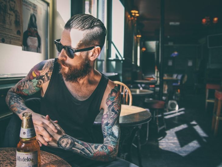 hombre con tatuajes trabajando en un bar